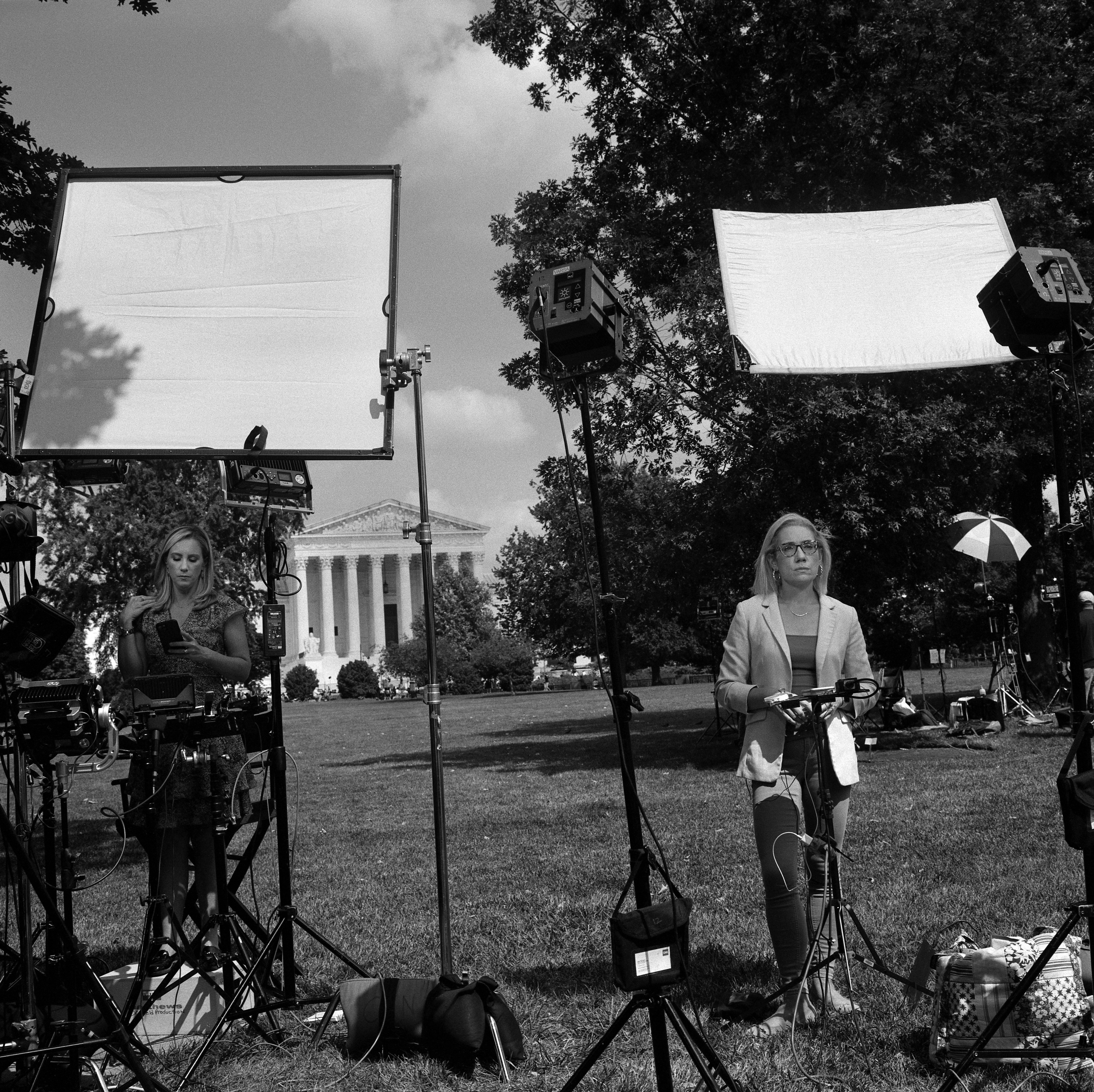 Wide angle of broadcaster waiting to go on air with equipment in foreground.