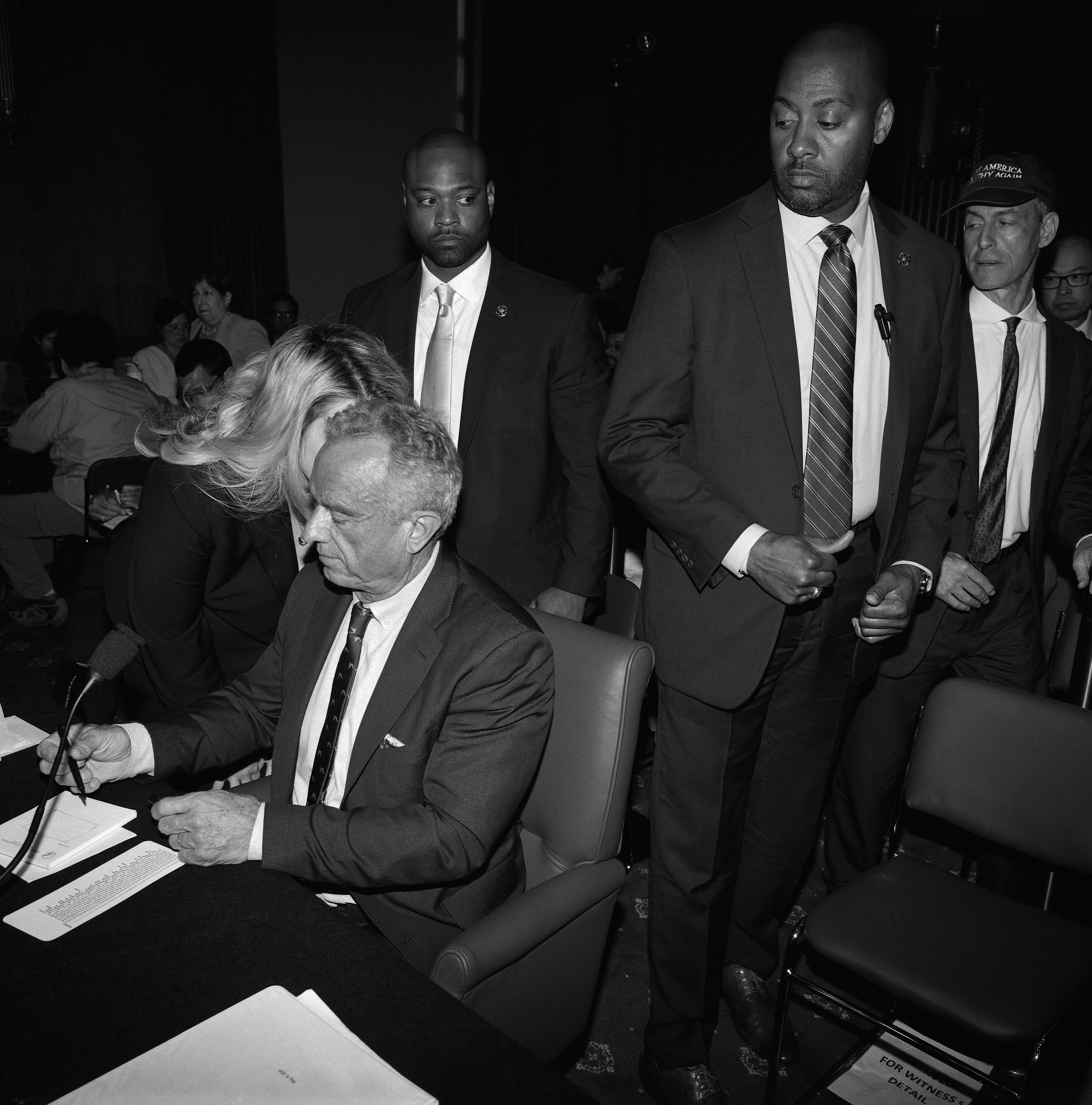 Health and Human Services Secretary Robert F. Kennedy Jr. seated with a person whispering in his ear.