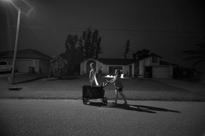 Woman pushes daughter in cart in middle of road.
