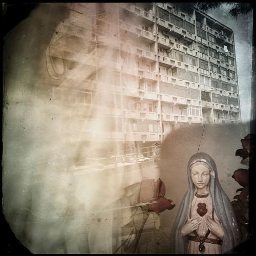 Librino apartment building facade with a reflection of Virgin Mary in foreground. 