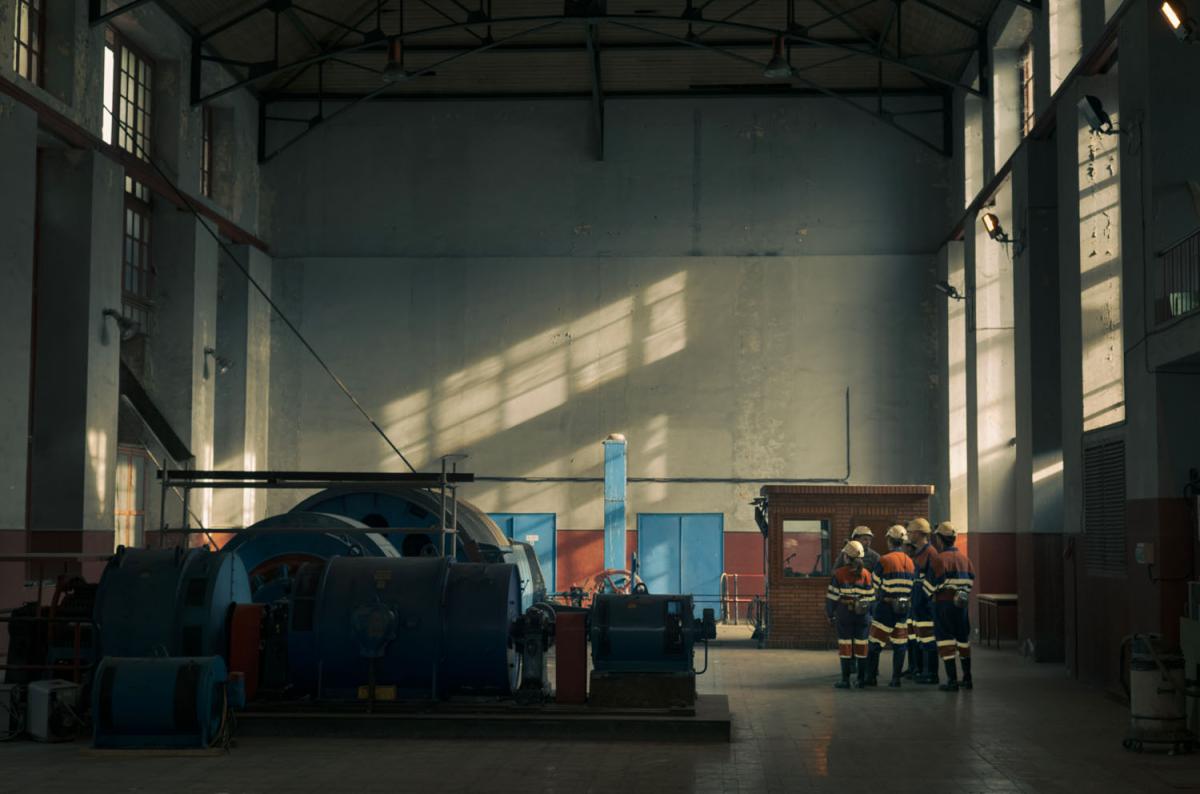 a handful of people in uniform in a large cavernous industrial space
