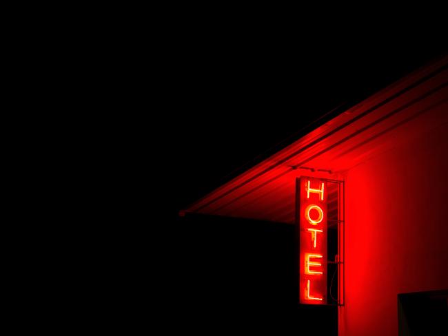 Photograph of sign reading "Hotel" glowing red in the night by Anna Beeke.